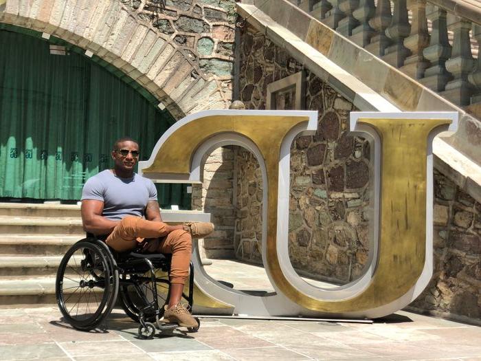 man in wheelchair near logo statue in 墨西哥