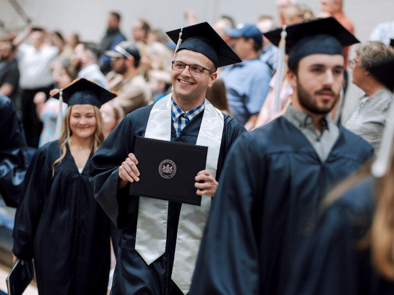 宾州州立大学新毕业生Kolton Lyons, 谁获得了工商管理副学士学位, proudly displays his degree to onlooking family and friends during the commencement ceremony at Penn State 杜波依斯.