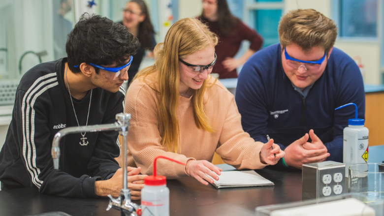 students examining a sample through a microscope