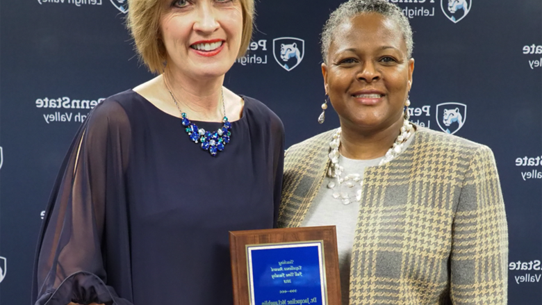 a woman handing a professor a plaque