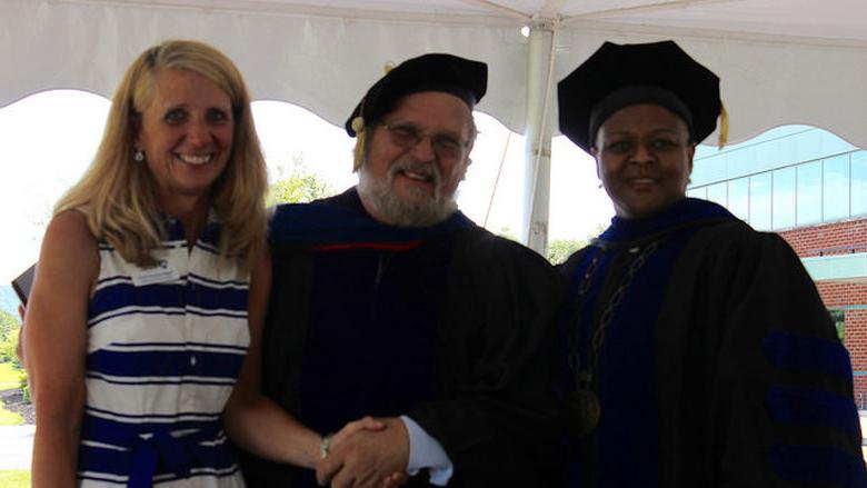 three people pose during award ceremony