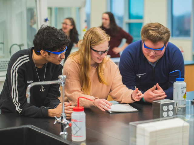 students examining a sample through a microscope